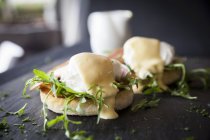 Hollandaise sauce over eggs benedict, breakfast on slate — Stock Photo