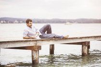 Älterer Mann entspannt sich auf Seebrücke — Stockfoto