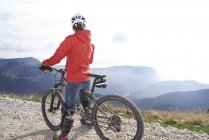 Вид ззаду велосипедиста на велосипеді, що дивиться на гори — стокове фото