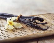 Vanilla pods and yellow flower on wooden board — Stock Photo
