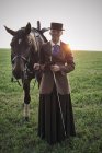 Портрет женщины, стоящей с выездной лошадью в поле — стоковое фото