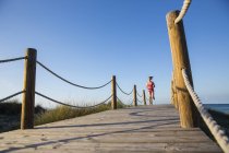 Junge Frau läuft auf Holzpfad, Sicht im Tiefflug — Stockfoto