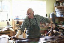 Travailleur masculin en atelier de cuir, contrôle des ceintures en cuir — Photo de stock