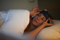 Femme mature portant un masque pour les yeux dans le lit de l'hôtel la nuit — Photo de stock