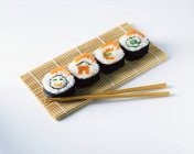 Sushis de saumon sur napperons avec baguettes en bois — Photo de stock