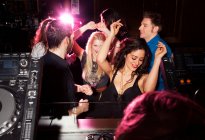 Grupo de amigos bailando delante de DJ en discoteca - foto de stock