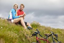 Cyclists relaxing and chatting on grassy hilltop — Stock Photo