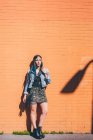Portrait of young woman with dip dyed blue hair leaning against orange wall — Stock Photo