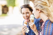 Друзі тримають морозиво конус посміхаючись — стокове фото