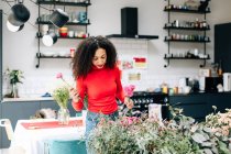 Female florist arranging flowers in small shop — Stock Photo