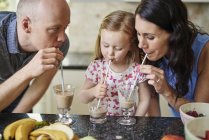 Family drinking smoothie with straws together — Stock Photo