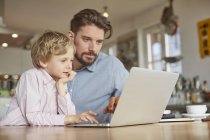 Pai e filho usando laptop no escritório em casa — Fotografia de Stock