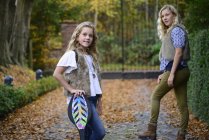 Portrait of two sisters with long blond hair in autumn park — Stock Photo