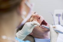 Над видом на плече стоматолога, який проводить огляд зубів на зрілого чоловіка — стокове фото