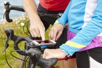 Велогонщики останавливаются, чтобы использовать GPS на мобильном телефоне — стоковое фото