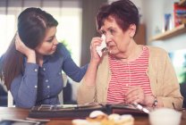 Young woman at table with grandmother crying while looking at photo album — Stock Photo