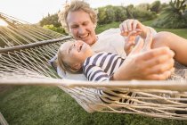 Father and son in garden lying in hammock laughing — Stock Photo
