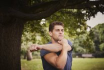 Young man training, warming up in park — Stock Photo