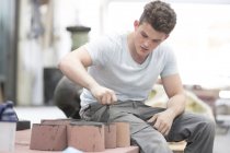 Young male foundry worker painting bronze sculpture in bronze foundry — Stock Photo