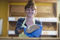 Portrait of young woman in bakery, holding fresh bread — Stock Photo