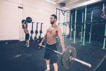 Junge männliche Crosstrainer Gewichtheben Langhantel in der Turnhalle — Stockfoto