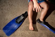 Cropped image of Young boy putting on flippers — Stock Photo