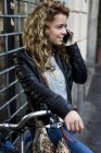 Женщина с велосипедом на улице делает телефонный звонок на мобильный телефон — стоковое фото