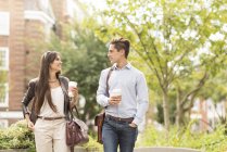 Young businessman and businesswoman walking and talking in city park — Stock Photo