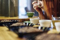 Close up woman tasting bowls of coffee at coffee shop tasting — Stock Photo