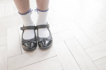 Cropped shot of schoolgirl wearing shoes and ankle socks standing on parquet floor — Stock Photo