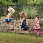 Enfants jouant avec saut à la corde sautant dans les airs — Photo de stock