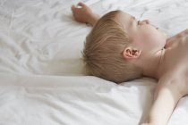 Босоніж хлопчик лежить на ліжку мріяв — стокове фото