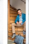 Мужчина с портфелем сидит на деревянной лестнице, держа телефон — стоковое фото