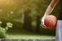 Обрезанная деталь молодого баскетболиста, держащего мяч — стоковое фото