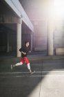 Junge Läuferin rast in sonnenbeschienene Stadtunterführung — Stockfoto
