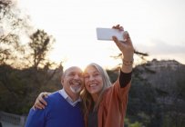 Pareja usando smartphone para tomar selfie sonriendo - foto de stock