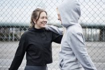 Two female runners warming up by wire fence — Stock Photo