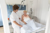 Nurse tending to patient in hospital bed — Stock Photo