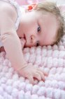 Baby girl lying on side sucking finger — Stock Photo