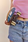 Девочка-подросток, на улице, держит скейтборд, средняя секция — стоковое фото