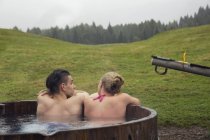 Rear view of young pour relaxing in rural hot tub, Sattelbergalm, Tyrol, Austria — стоковое фото