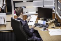 Geschäftsmann liest Papierkram am Schreibtisch — Stockfoto
