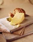 Wedge of mature cheese with apple slice and crusty wholemeal roll on wooden cutting board — Stock Photo