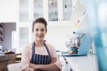 Portrait of young female baker in kitchen — Stock Photo