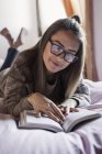 Junge Frau entspannt sich im Bett, liest Buch — Stockfoto