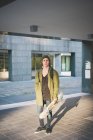 Retrato de joven patinador urbano fresco sosteniendo monopatín - foto de stock