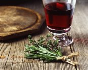 Букет розмарина и тимьяна, завязанных веревкой, красным бокалом вина — стоковое фото