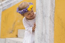 Female toddler wearing floral headdress peering from stairway, Beja, Portugal — Stock Photo