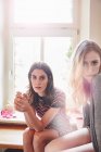 Портрет двох молодих жінок, що сидять на кухонній стійці — стокове фото