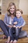 Ritratto di madre e figlio, seduto sul pavimento, sorridente — Foto stock